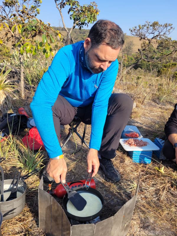 Pedro cozinhando com um fogareiro multi combustível da Primus