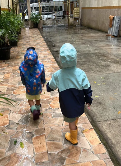 Crianças encarando um dia de chuva do lado de fora